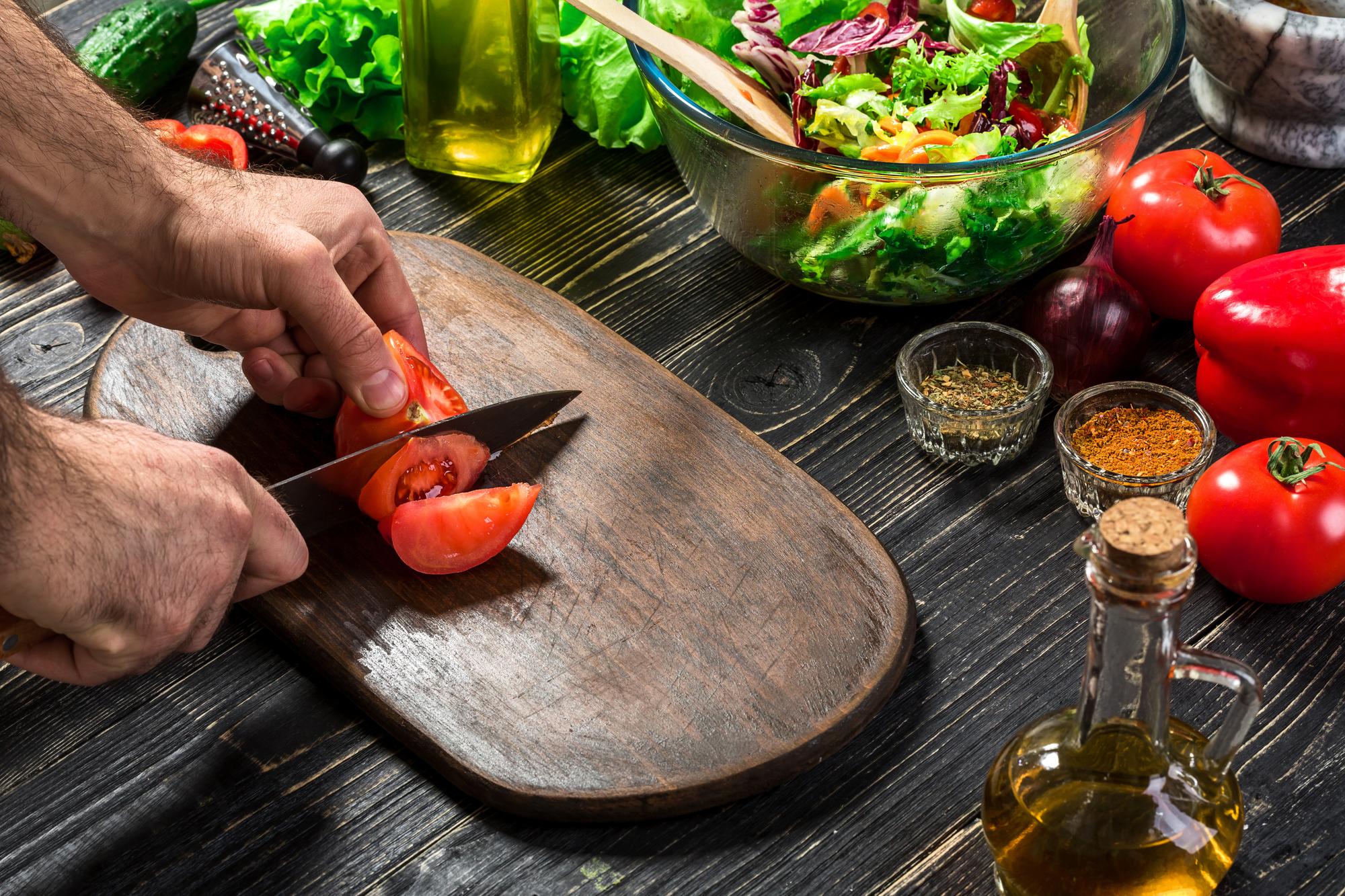 Artisan chef slicing seasonal vegetables on wooden board
