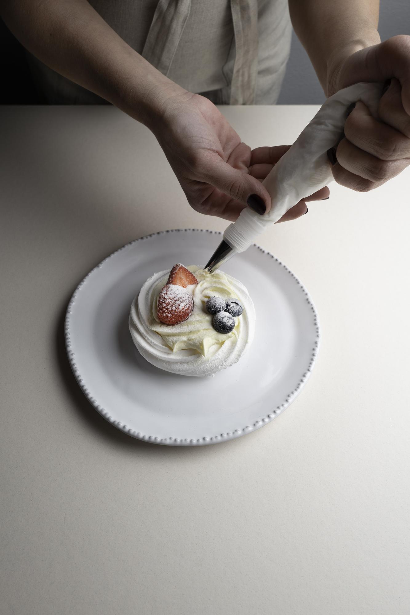 Chef hands arranging dessert on ceramic plate